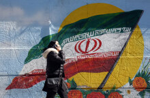 Ιρανή μιλά στο κινητό της τηλέφωνο περνώντας μπροστά από ένα γκράφιτι με τη σημαία του Ιράν στην πρωτεύουσα Τεχεράνη