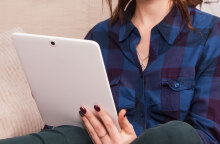 Κοπέλα με καρό πουκάμισο κρατάει τάμπλετ