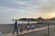 Γυναίκα περπατά σε παραλία με τρία παιδιά