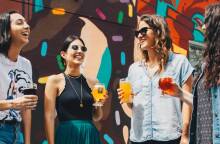 Τέσσερις φίλες που πίνουν ποτό, συζητάνε και γελάνε