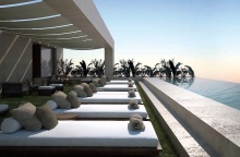 Ξαπλώστρες σε rooftop ξενοδείου με infinity πισίνα μπροστά τους