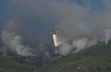 Μεγάλη φωτιά στην Κορινθία, με ελικόπτερο της Πυροσβεστικής να ρίχνει νερό πάνω από εστία της πυρκαγιάς που καίει το δάσος