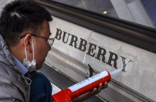 Ένας άντρας επισκευάζει κατεστραμμένο λογότυπο μπροστά από το κατάστημα Burberry στη Σαγκάη της Κίνας, στις 26 Μαρτίου 2021.