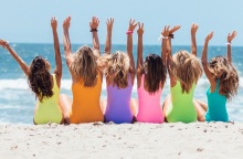 Γυναίκες με μαγιό στην παραλία που σηκώνουν τα χέρια ψηλά