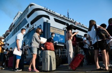 Ταξιδιώτες αναμένουν την επιβίβασή τους σε πλοίο κρατώντας στα χέρια κινητό ή έγγραφα που χρειάζονται