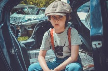 Παιδί με μπερέ που κάθεται σε αυτοκίνητο