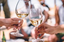 Δυο κορίτσια κρατούν ποτήρια με λευκό κρασί.