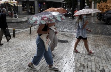 Γυναίκες προστατεύονται από την καταιγίδα κρατώντας ομπρέλα