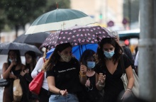 Πολίτες κρατούν ομπρέλα για να προστατευτούν από τον βροχερό καιρό