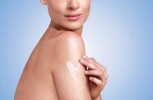 Γυμνή γυναίκα απλώνει ενυδατική κρέμα στο μπράτσο της