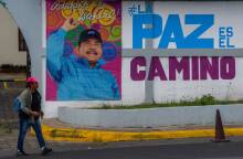 Μια γυναίκα περπατά μπροστά από διαφημιστική αφίσα με την εικόνα του Προέδρου της Νικαράγουας, Ντάνιελ Ορτέγκα