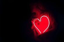 Άνθρωπος που κρατά μια φωτεινή επιγραφή σε σχήμα καρδιάς