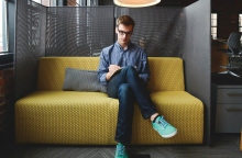 Νεαρός άντρας στον καναπέ εταιρείας, κρατάει σημειώσεις