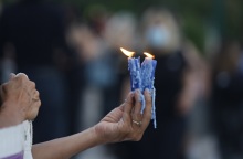 Γυναικείο χέρι που κρατά δύο αναμμένα κεριά σε εξωτερικό χώρο