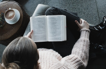 Κοπέλα κάθεται στον καναπέ και διαβάζει βιβλίο