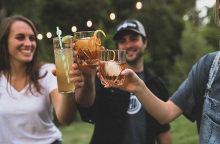 3 νεαροί φίλοι τσουκγρίζουν τα ποτήρια με το ποτό τους