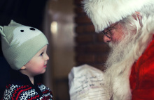 Ένα μικρό παιδάκι στέκεται μπροστά από τον Άγιο Βασίλη