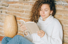 Μια κοπέλα διαβάζει βιβλίο στο κρεβάτι