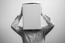 Ασπρόμαυρη φωτογραφία με έναν άντρα που έχει βάλει ένα κουτί στο κεφάλι του