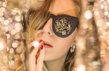 Γυναίκα με γυαλιά ηλίου ανάμεσα σε χρυσά χριστουγεννιάτικα λαμπάκια