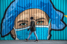 Πολίτης με μάσκα για τον κορωνοϊό μπροστά από mural για την πανδημία Covid στο Παρίσι