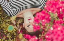 Ένα κορίτσι ποζάρει κάτω από λουλούδια. 