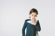 Ένα παιδί κρατάει ένα χαρτομάντηλο και κοιτάει την κάμερα. 