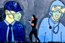 Κοπέλα κάνει τζόκινγκ, περνώντας μπροστά από mural για τον κορωνοϊό