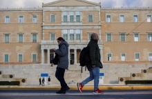 Άνδρας και Γυναίκα περπατούν στο κέντρο της Αθήνας με φόντο τη Βουλή των Ελλήνων