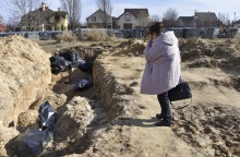 Γυναίκα στέκεται συγκλονισμένη πάνω από ομαδικό τάφο στην Μπούκα της Ουκρανίας