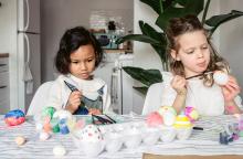 Δύο μικρά κοριτσάκια βάφουν πασχαλινά αυγά