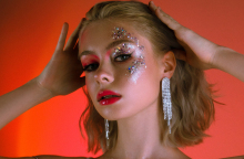 Κοπέλα με ξανθό καρέ μαλλί και στρας στο πρόσωπο που πιάνει το κεφάλι της