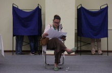 Συνέδριο ΠΑΣΟΚ-ΚΙΝΑΛ: Γυναίκα διαβάζει φυλλάδιο καθισμένη σε καρέκλα ανάμεσα στα δύο παραβάν