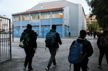 Μαθητές με τις σχολικές τους τσάντες περνούν την είσοδο του σχολείου τους