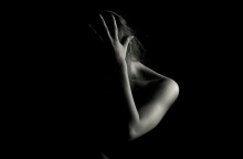 Γυναίκα φωτογραφίζεται με το χέρι στο πρόσωπο σε σκοτάδι - Φαίνεται ο ώμος και το χέρι της