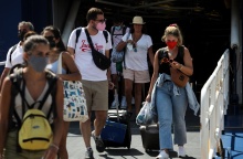 Επιβάτες αποβιβάζονται από πλοίο φορώντας μάσκες