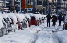 Κακοκαιρία «Ελπίδα»: Πολίτες περπατούν πάνω στη Μεσογείων λόγω του χιονιού που βρίσκεται στα πεζοδρόμια
