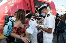 Ταξιδιώτες αναμένουν την επιβίβασή τους σε πλοίο κρατώντας στα χέρια κινητό ή έγγραφα που χρειάζονται 