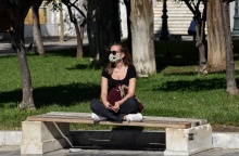 Κοπέλα που φορά μάσκα καθισμένη στο παγκάκι στο κέντρο της Αθήνας