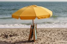 Ομπρέλα ανοιχτή σε παραλία με δύο ομπρέλες μαζεμένες