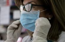 Γυναίκα με μάσκα και γάντια για την προστασία της από τη γρίπη