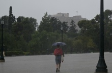 Άτομο σε δρόμο της Αθήνας κρατά ομπρέλα για να προστατευτεί από ισχυρή καταιγίδα