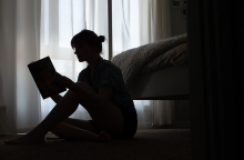 Κοπέλα καθισμένη στο πάτωμα διαβάζει βιβλίο