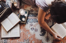 Άντρας ξαπλωμένος μπρούμυτα στο πάτωμα διαβάζει βιβλίο