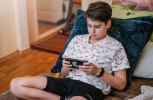 Έφηβος κρατά το κινητό του ενώ κάθεται σε μαξιλάρια