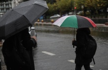 Άνδρας κρατά ομπρέλα περπατώντας στον δρόμο για να προστατευτεί από καταιγίδα