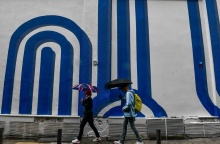 Πολίτες με ομπρέλα προστατεύονται από τη βροχόπτωση σε δρόμο της Αθήνας