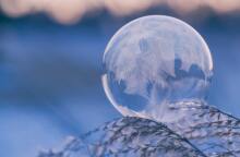 Γυάλινη μπάλα με πούπουλα πάνω σε χιονισμένο κλαδί