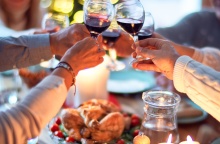 Άτομα τσουγκρίζουν τα ποτήρια με το κρασί τους στο χριστουγεννιάτικο τραπέζι