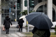Πολίτες με ομπρέλα κατά τη διάρκεια ελαφράς χιονόπτωσης στο κέντρο της Αθήνας